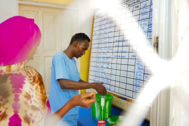 Abdi Bare Abdi, assistant nutritionnel à l'hôpital régional de Bay, soutenu par MSF, mesure le lait thérapeutique pour une mère dont l'enfant est soigné pour malnutrition à Baidoa, en Somalie. Mars 2025