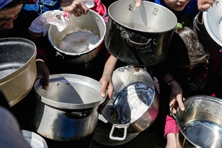 Des enfants tenant leurs pots vides dans une cuisine communautaire dans le nord de Gaza, février 2025