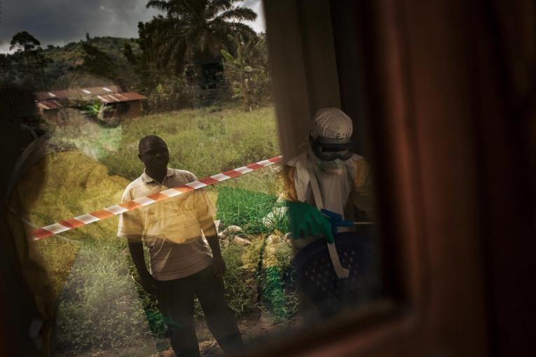 Un laborantin observe le travail des équipes MSF et regarde notamment comment ils vont réussir à désinfecter le microscope et les outils de son laboratoire. Certains éléments comme le papier seront brûlés car impossible à décontaminer. République démocratique du Congo. 2018.