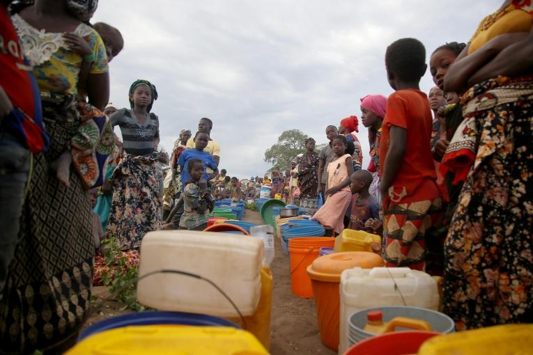 Des dizaines de personnes déplacées patientent après l'approvisionnement de 8 000 litres d'eau par camion dans un espace ouvert à la périphérie de Mueda,