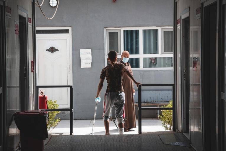 Un jeune homme de 18 ans, blessé lors d'un accident de moto, marche dans une structure MSF de Mossoul-Est. Irak. 2022.