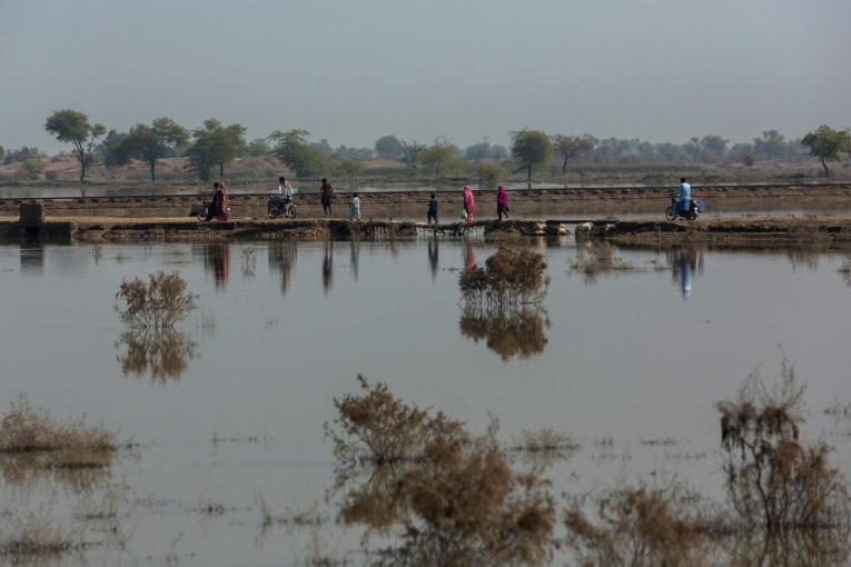 Des villageois traversant une route endommagée par les eaux le long d'un village près de la ville de Garhi Khairo, dans le district de Jacobabad, dans la province du Sindh au Pakistan, le 28 octobre 2022.