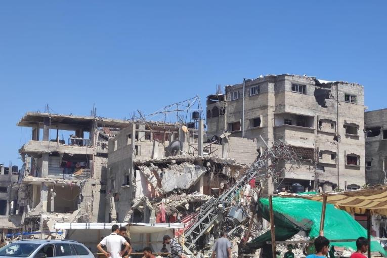 Des personnes se tiennent devant un bâtiment bombardé à Rafah