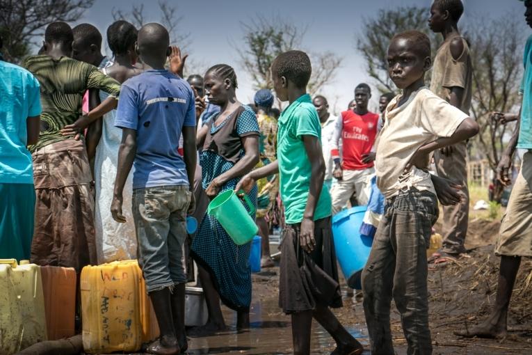 Dans le camp de Palorinya des réfugiés viennent chercher de l'eau alors que le camion citerne est embourbé. La saison des pluies risque de rendre l'approvisionnement en eau potable difficile.
