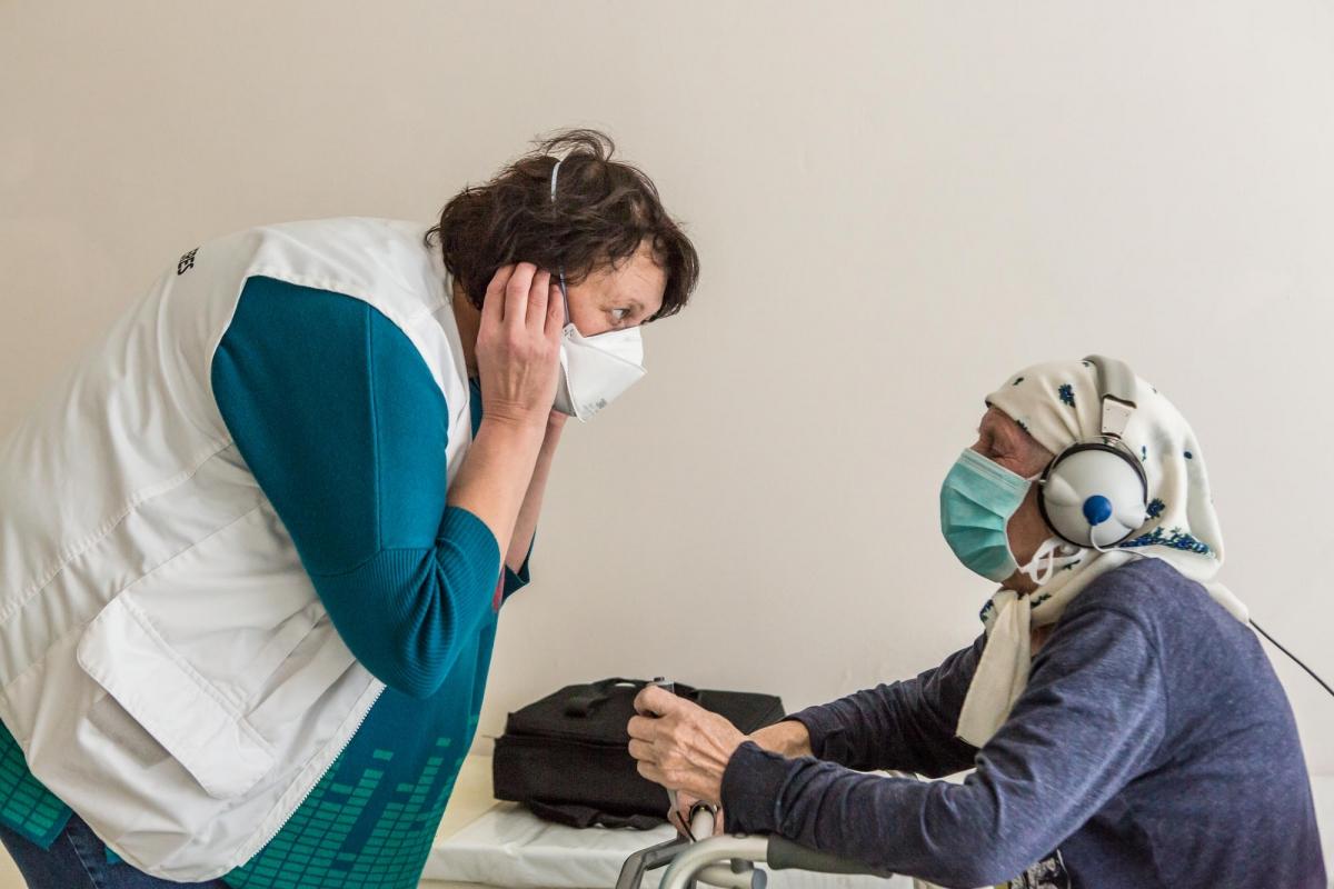 Olena est une infirmière MSF. Elle effectue des tests d'audition sur une patiente. Elle s'appelle Lidjia et a 78 ans. Ukraine. 2018.
 © Oksana Parafeniuk