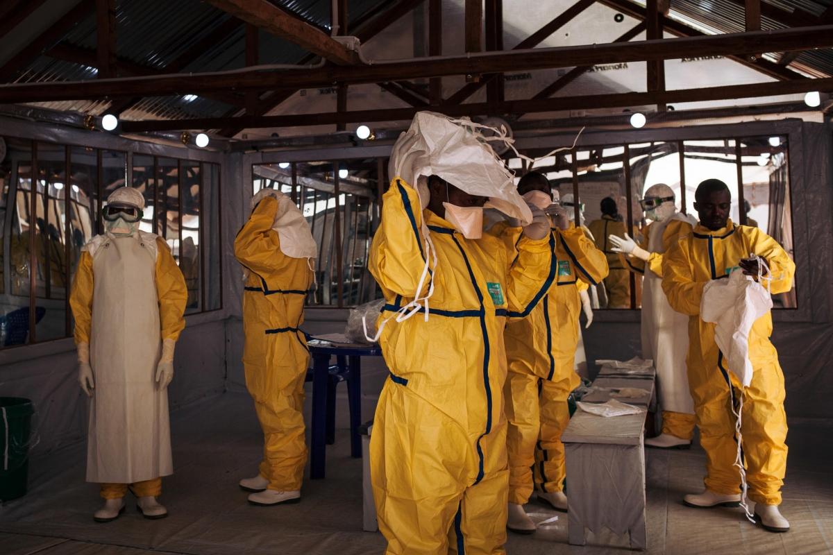 Des travailleurs de santé MSF revêtent leur équipement de protection individuel avant d'entrer dans la zone à risque du centre de traitement Ebola. République démocratique du Congo. 2018. 
 © Alexis Huguet