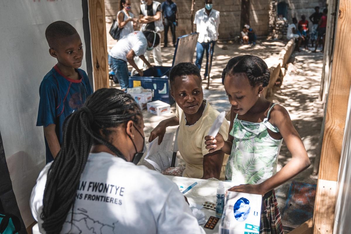 Annette et ses trois enfants en consultation avec un docteur MSF dans le cadre d'une clinique mobile installée au Parc Celtique, un site informel de personnes déplacées. Port-au-Prince. Haïti. 2021.
 © Pierre Fromentin/MSF