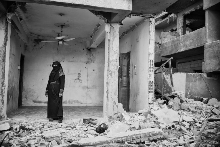 Une femme regarde ce qui a été un jour sa maison, en ruine après les offensives sur Rakka.
 © Eddy Van Wessel
