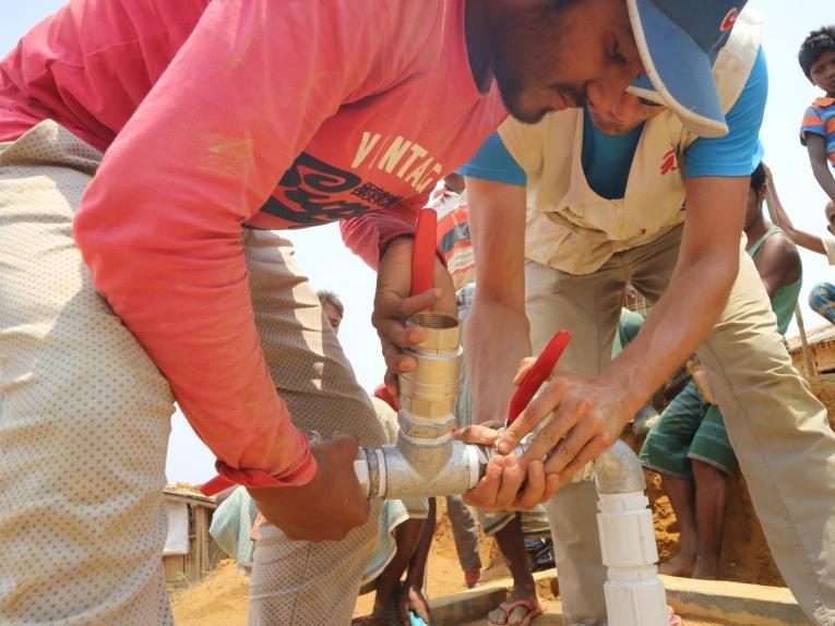 Arafat Hosen (à gauche), superviseur du réseau de distribution d’eau chez MSF, et Thibault Chazal, logisticien MSF, conduisent l'installation d'une pompe à eau submersible dans un puit profond.
 © MSF