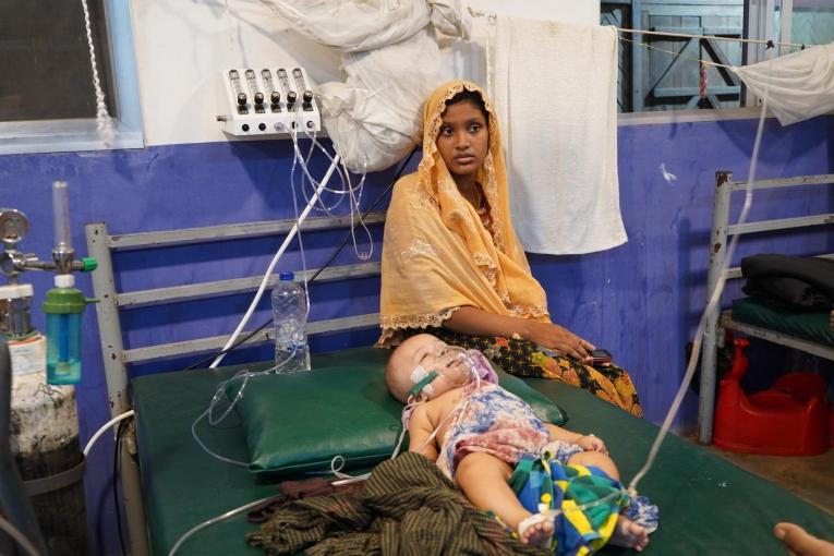 La mère d’un enfant admis dans le centre médical de MSF à Kutupalong est assise sur son lit. Deux ans après les violences d'aout 2017, les réfugiés continuent de vivre dans des conditions précaires. Bien que l'accès à la nourriture, à l'eau et aux soins de base se soit amélioré, il reste insuffisant et inégalement réparti dans les camps. 
 © Dalila Mahdawi/MSF