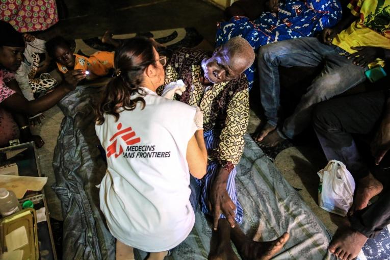 L'infirmière Nathalie Kornfein change le pansement de Maady Dabo, un patient âgé de 76 ans atteint d'un cancer oral. Pendant les soins, il est entouré par sa famille. Mali. 2019. 
 © MSF/Mohammad Ghannam