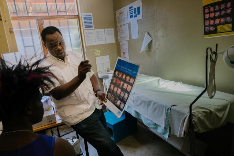 Prince Nkhoma explique le processus de dépistage du cancer du col de l'utérus à une jeune femme de 22 ans dans un dispensaire MSF pour les professionnel.le.s du sexe, intégré à l'hôpital de district de Mwanza. Le risque de développer un cancer du col de l'utérus est particulièrement élevé chez les professionnel.le.s du sexe : une mauvaise utilisation du préservatif et de multiples partenaires sexuels entraînent une transmission plus élevée du virus HP (HPV), qui provoque le cancer du col. Malawi. 
 © Isabel Corthier