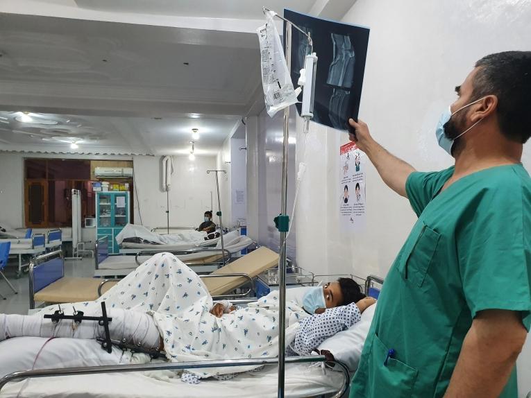 Dans le centre de traumatologie de Kunduz, un infirmier examine la radio d'un patient qui a subi une fracture de la partie supérieure et inférieure de la jambe suite à une explosion.
 © Stig Walravens/MSF