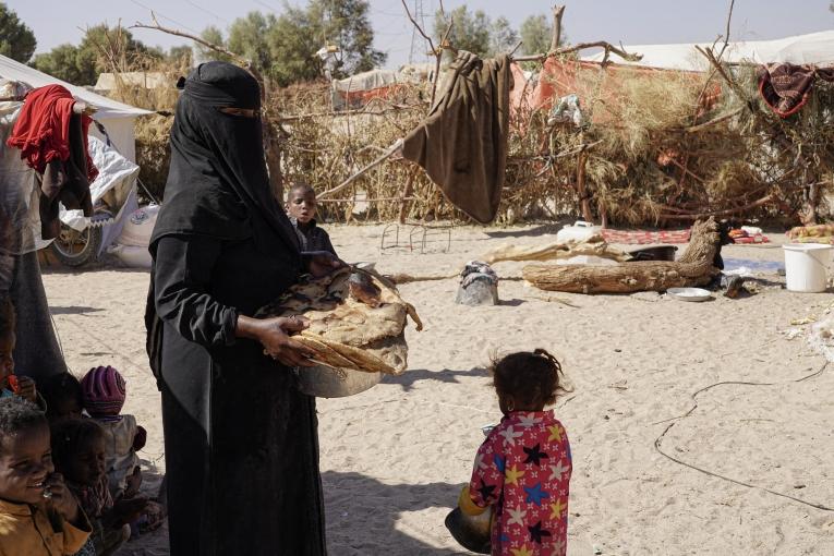 Une femme transporte du pain pour le petit-déjeuner. Camp de déplacés à Al-Khuseif à Marib. Yémen. 2021.
 © Hesham Al Hilali