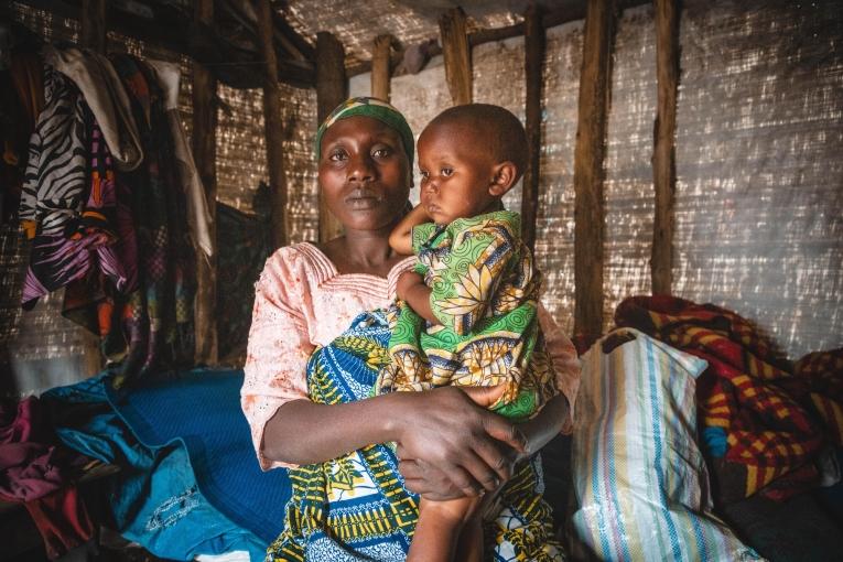 Sifa tient sa fille Tamuriza dans ses bras, assise dans leur tente faite de bois et de bâches sur le site de déplacés de Katale, dans le territoire de Masisi. 
 © MSF/Laora Vigourt