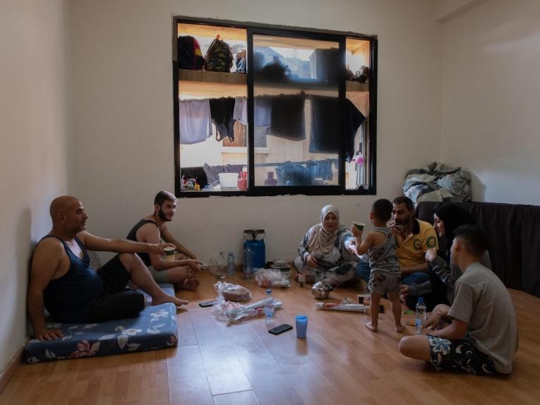 Une famille de personnes déplacées partage un repas dans leur chambre de l'abri d'Azarieh à Beyrouth. 
 © Antoni Lallican/Hans Lucas