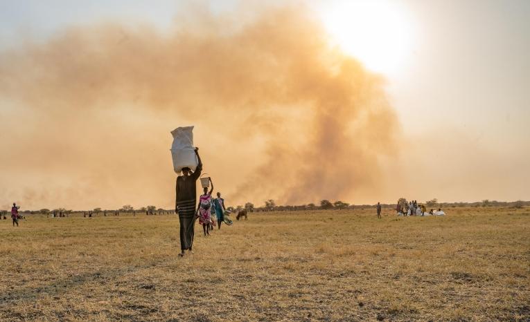 Une femme transporte des sacs de nourriture sur la tête après un largage de vivres effectué par le Programme alimentaire mondial près de Chuil.
 © Isaac Buay/MSF