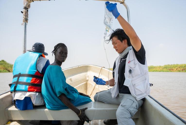 Joon Hyun, membre du personnel de MSF, tient une perfusion intraveineuse destinée à un patient transféré par bateau vers le centre de soins de santé primaires de Chuil, pour obtenir des soins complémentaires.
 © Isaac Buay/MSF