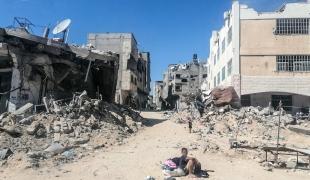 Un enfant assis au milieu de bâtiments détruits, Gaza, juin 2024.