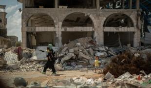 Dans le quartier de Shujaeyya, rue Bagdad, à Gaza, une femme ramène son enfant à la maison à travers les décombres. ©Motassem Abu Aser