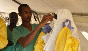 Les membres de l'équipe médicale s'habillent avec des vêtements de protection avant d'entrer dans la structure de soins. 1er avril 2014