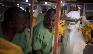 Un travailleur de santé revêt son masque avant d'entrer dans la zone à risque d'un centre de traitement Ebola. Novembre 2018. République démocratique du Congo.