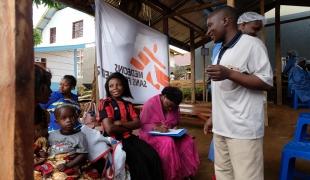 Joseph MbokaniI Kambale, l’un des agents de sensibilisation déployés par le dispositif national de réponse à Ebola, répond aux questions des participants. Les craintes et les rumeurs découragent de nombreuses personnes de se faire vacciner. République démocratique du Congo. 2019.