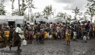Des personnes déplacées du camp de Rusayo font la queue pour collecter de l'eau.