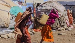 Des femmes transportent des bidons alors qu'elles reviennent du point de distribution d'eau du camp de personnes déplacées de Banban, à Baidoa, en Somalie.