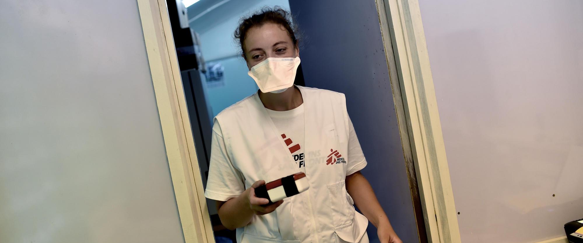 La responsable de laboratoire de MSF, Lise Marchand, entre dans le laboratoire après avoir recueilli l'échantillon d'expectoration du drone à l'extérieur.